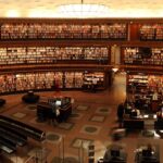 Panoramic view of a grand circular library with shelves full of books and study desks.